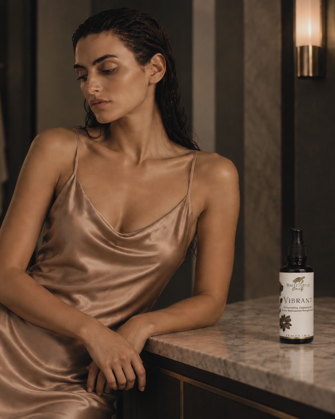 A woman leans on a marble counter next to a bottle of VIBRANT cleansing oil