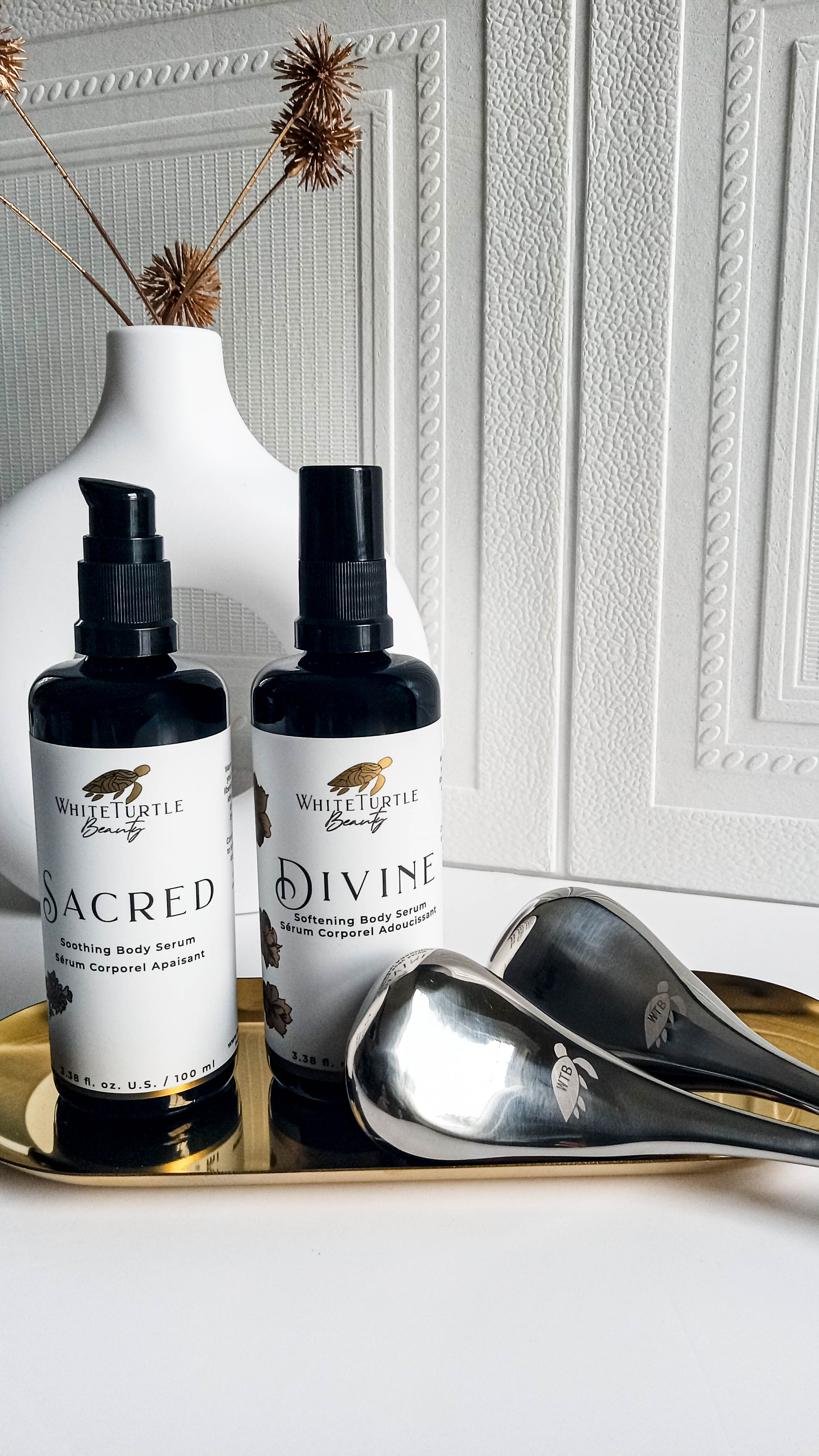 Stainless steel cryotherapy wands alongside luxury body oil serums