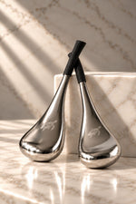 Two metallic massage tools with black handles and engraved turtle logos