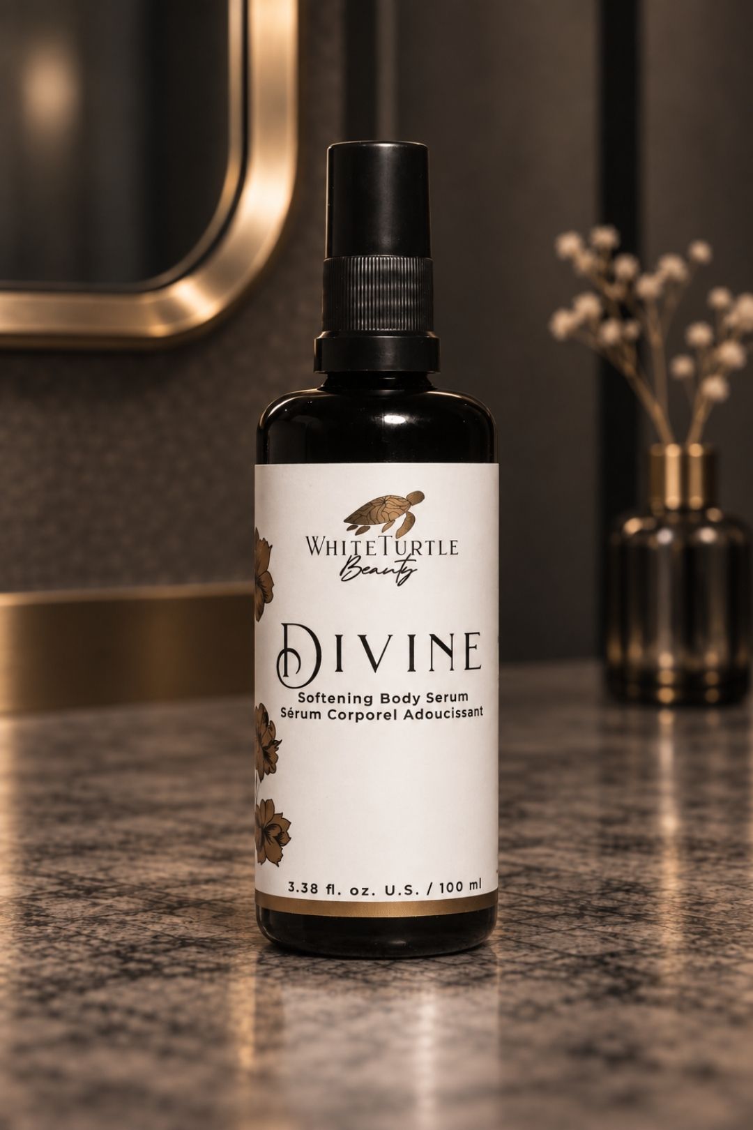 A bottle of White Turtle Beauty Divine Softening Body Serum stands on a dark marble countertop in a bathroom 