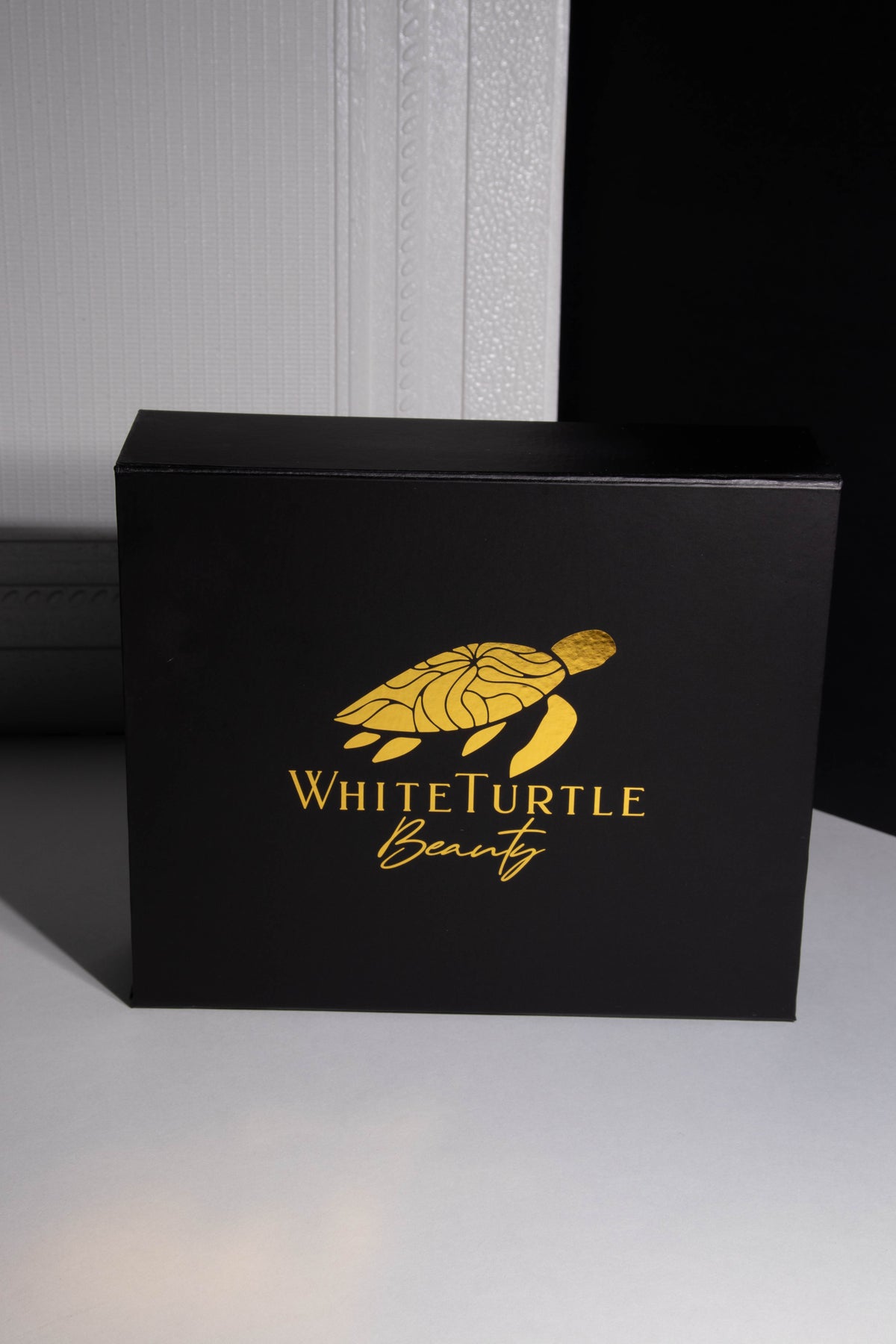 Black box with gold 'White Turtle Beauty' logo on a gray background