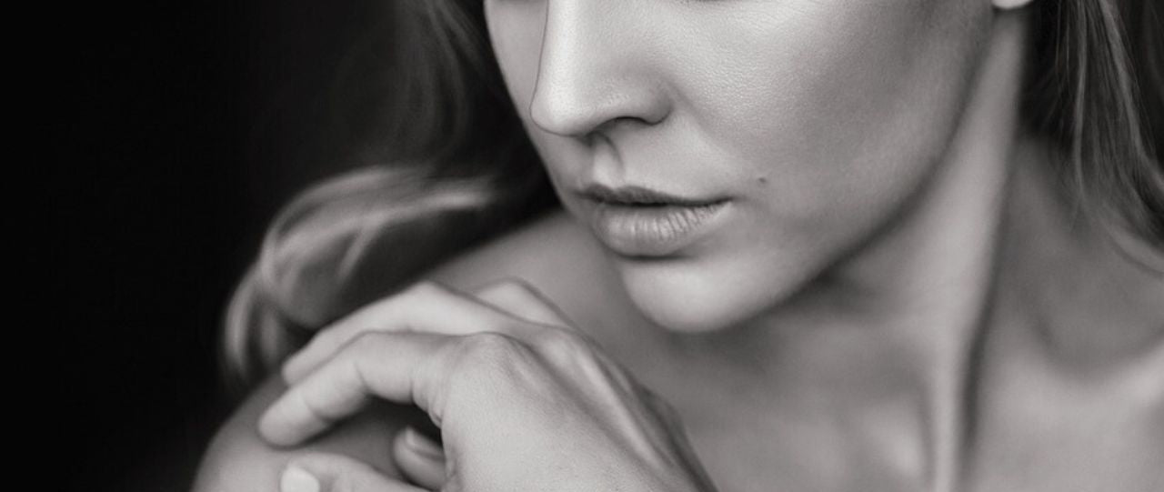 Black and white close-up of a woman holding her shoulder with a soft focus background
