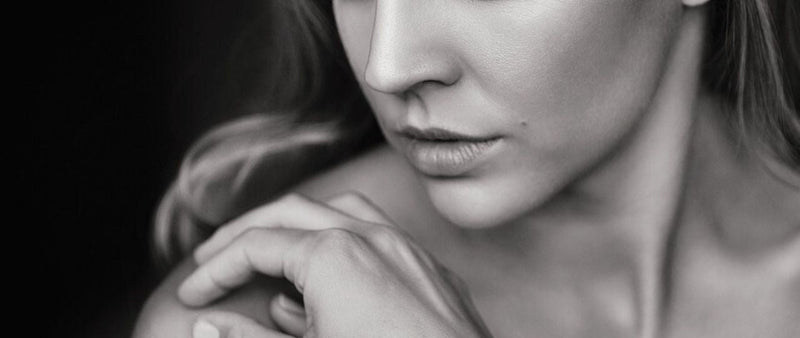 Black and white close-up of a woman holding her shoulder with a soft focus background
